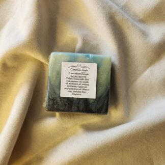 soap bar with splashes of black, greens, and blues, and the product label